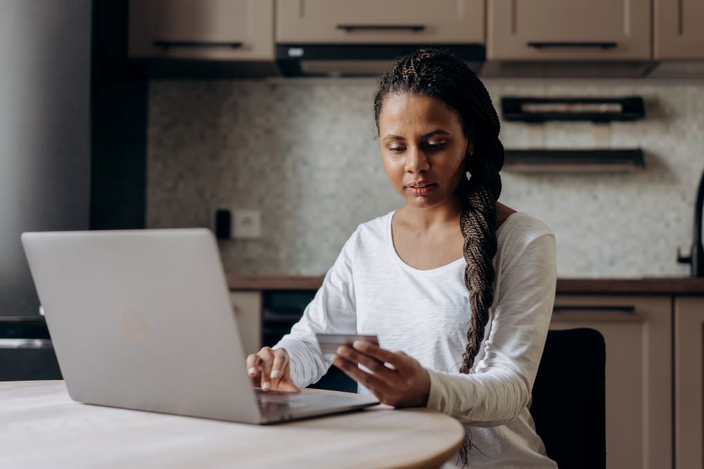 woman thinking about using a credit card at her laptop